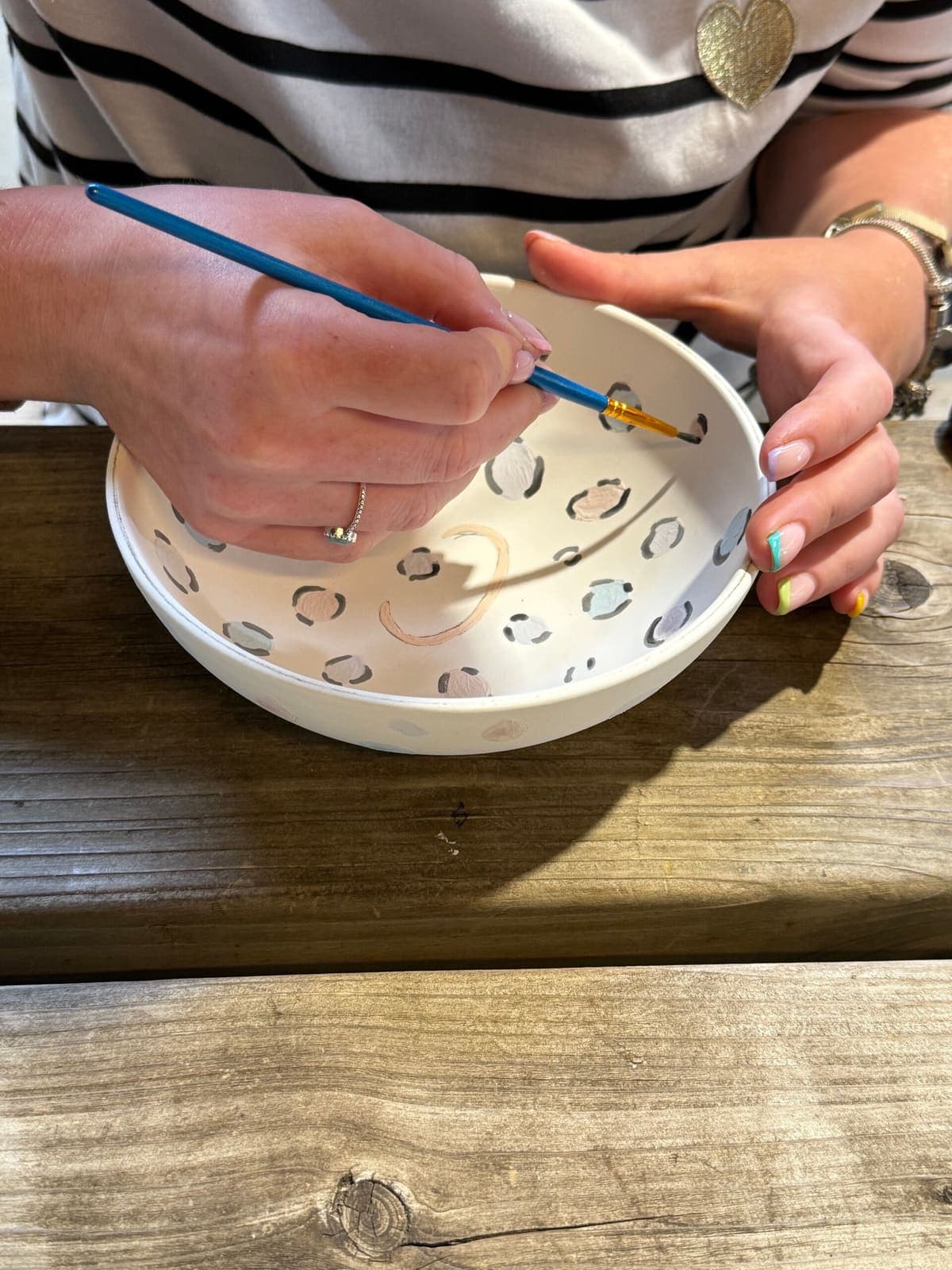 Deelnemer beschildert een kom met panterprint tijdens een workshop